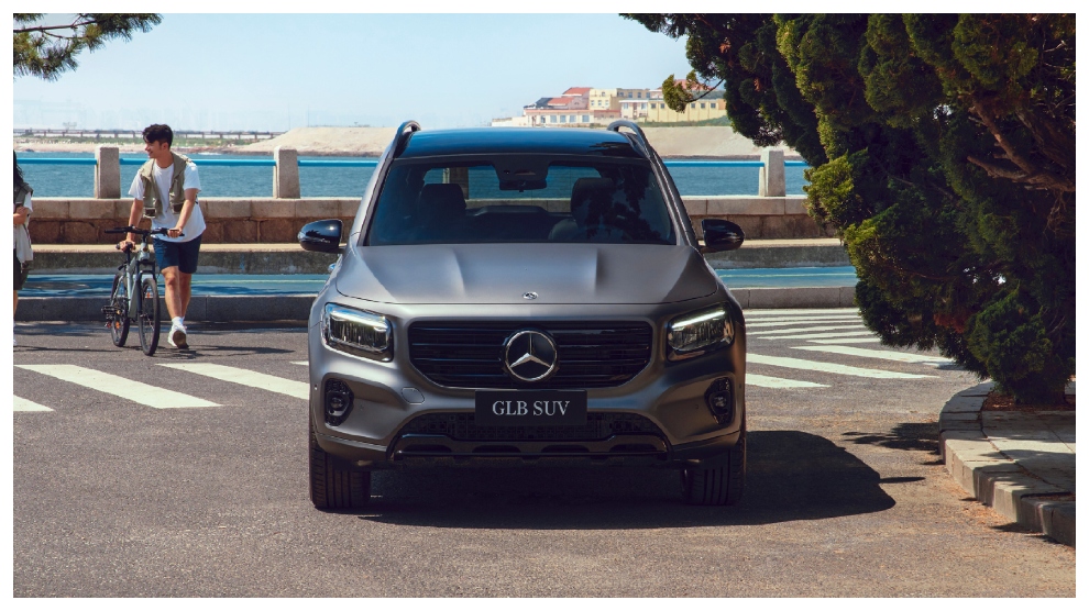 <p>SUV hibrida Mercedes-Benz GLB 200 gris aparcada en la vía con el mar al fondo.</p>