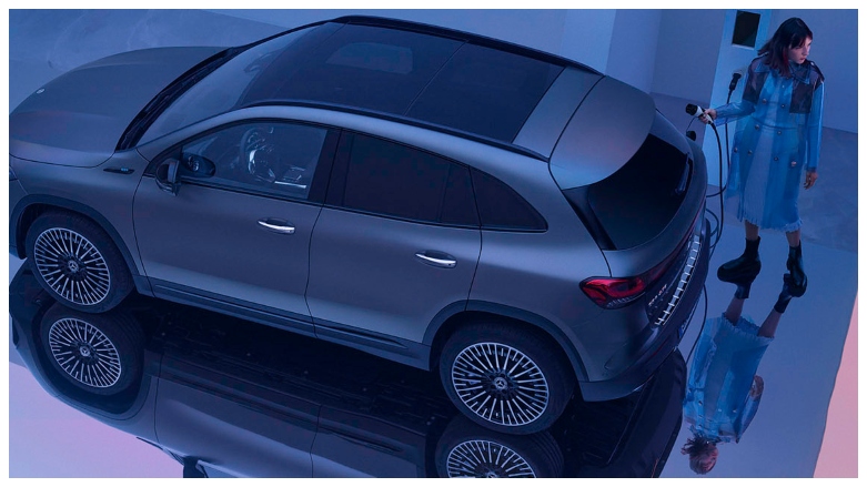 Mujer cargando un SUV eléctrico de lujo Mercedes-Benz EQA con un cargador de pared.