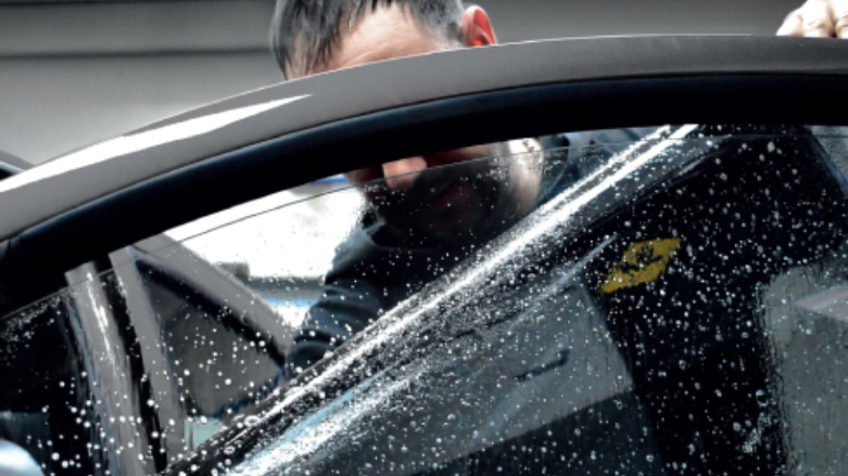 Técnico disponiendo una lámina de seguridad para la ventana de un auto. 