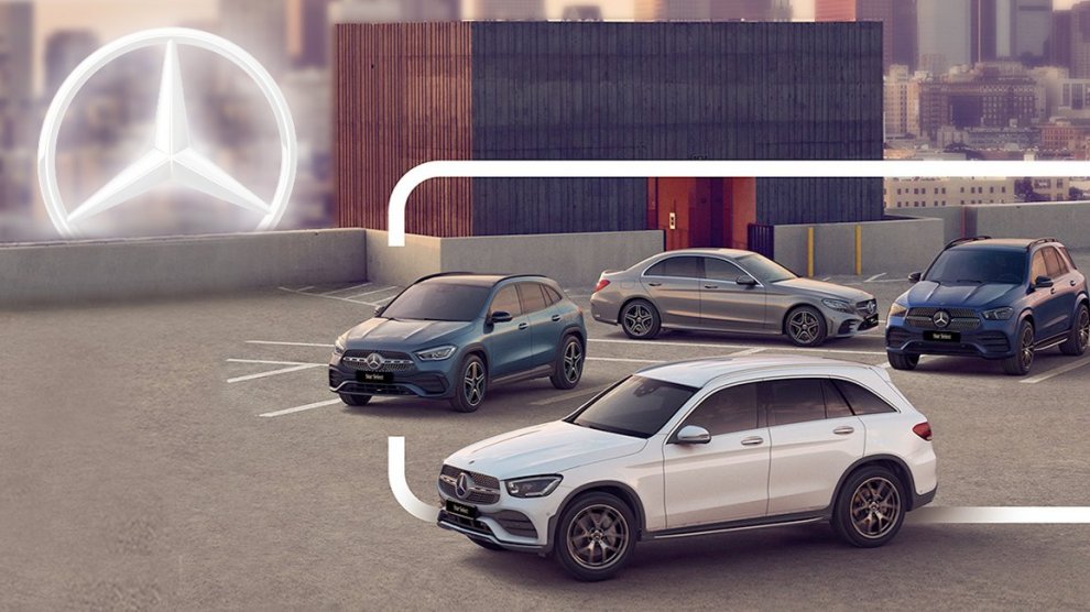 <p>Vehículos Mercedes-Benz estacionados en estacionamiento con ciudad de fondo.</p>