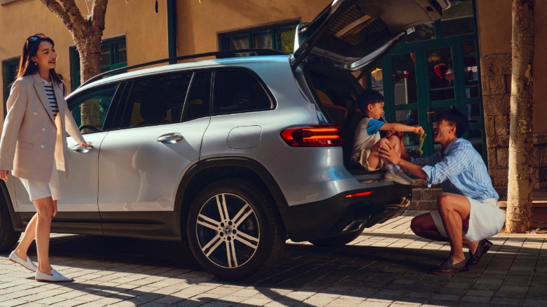 <p>SUV Mercedes-Benz GLB 7 pasajeros color plateado con el baúl abierto y un padre y su hijo en ella.</p>
