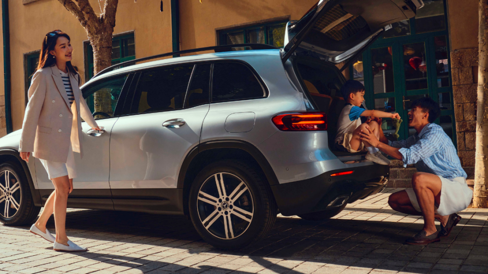 <p>SUV Mercedes-Benz GLB 7 pasajeros color plateado con el baúl abierto y un padre y su hijo en ella.</p>