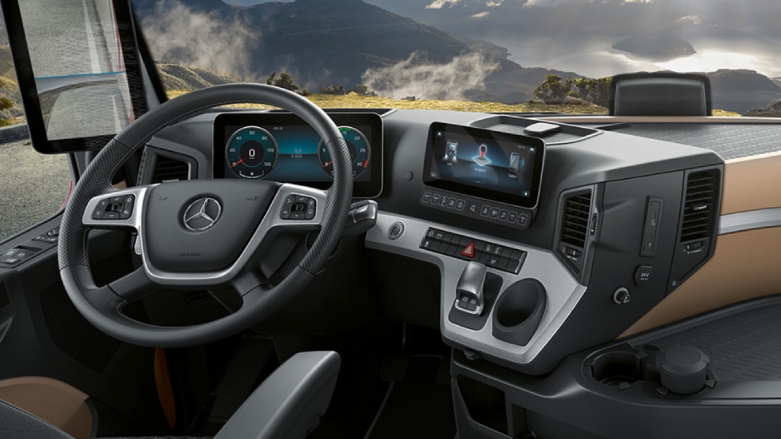 Vista interior de camión Mercedes-Benz Actros con pantallas táctiles y asiento de lujo.